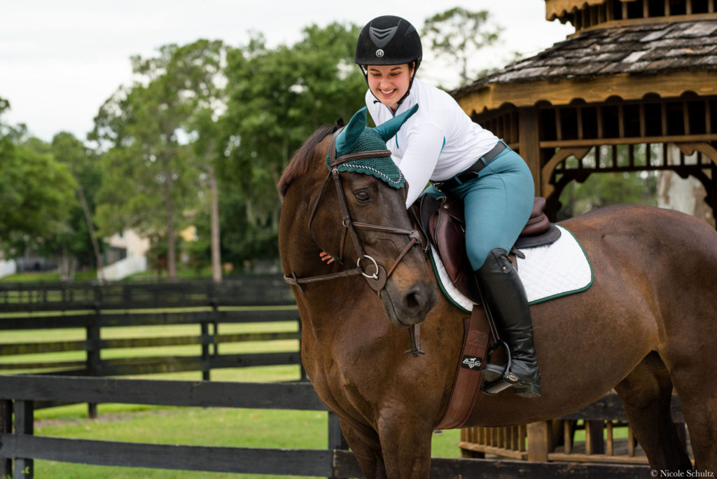 Girl-Wearing-One-K-Helmet-With-White-Tailored-Sportsman-Ice-Fill-Shirt-And-Trophy-Hunter-Breeches-With-Ariat-Tall-Boots-CWD-Saddle-And-Green-Jump-Mantra-Bonnet-With-Brown-Warmblood-Mare