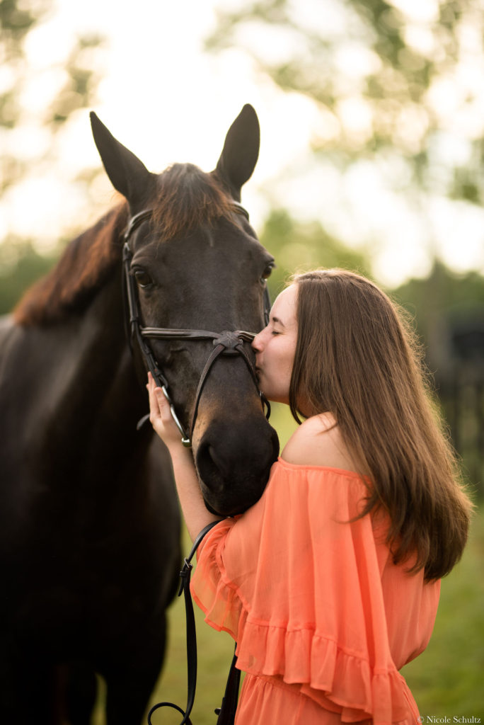 Brunette-Girl-Wearing-Orange-Romper-Giving-Kisses-To-Brown-Warmblood-Mare-Horse
