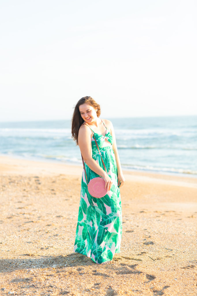 Brunette-Girl-Wearing-BuddyLove-Sirens-Song-Green-And-Pink-Tropical-Print-Maxi-Dress-With-Pink-Wicker-Round-Bag-At-Florida-Beach