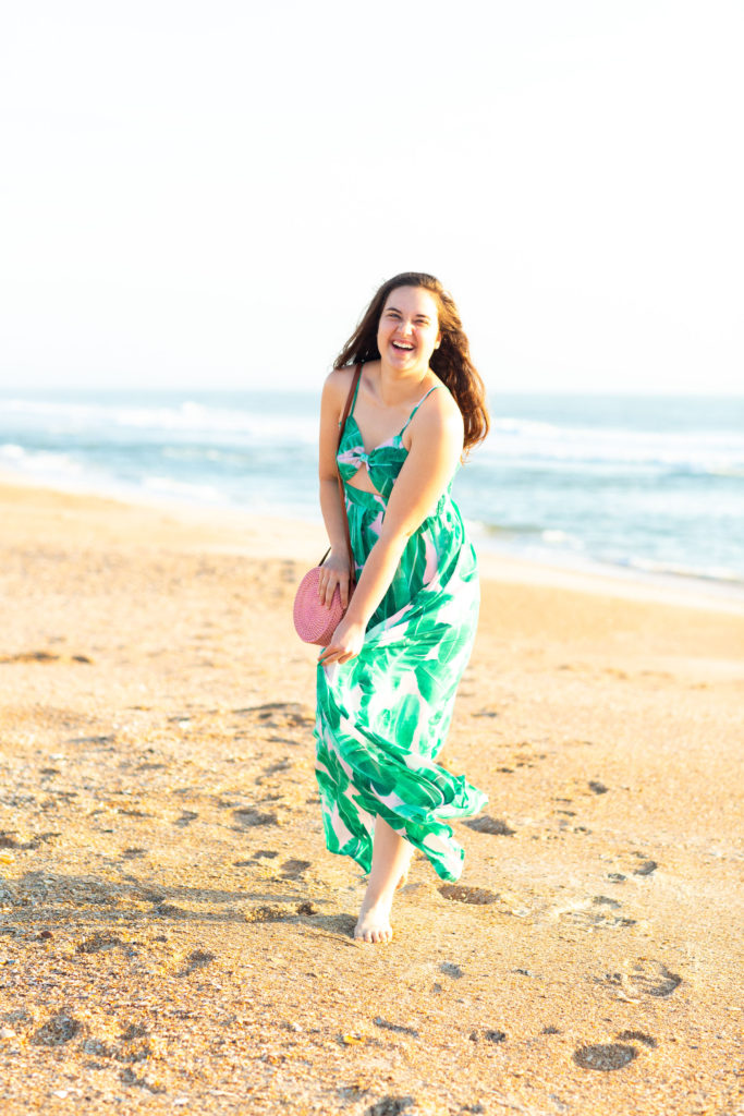 Brunette-Girl-Wearing-BuddyLove-Sirens-Song-Green-And-Pink-Tropical-Print-Maxi-Dress-With-Pink-Wicker-Round-Bag-At-Florida-Beach