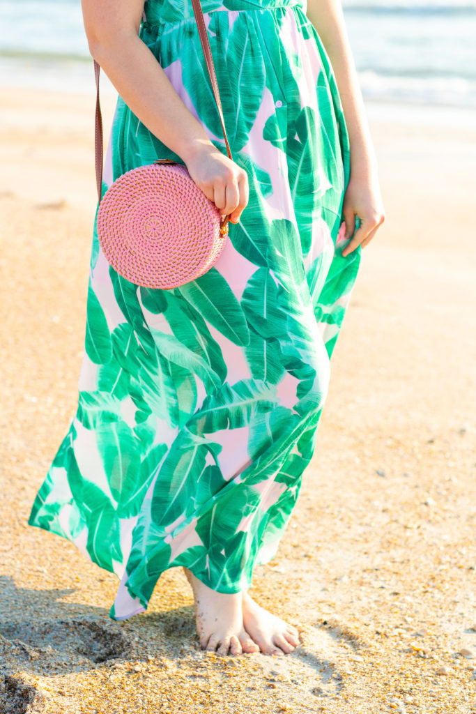 Brunette-Girl-Wearing-BuddyLove-Sirens-Song-Green-And-Pink-Tropical-Print-Maxi-Dress-With-Pink-Wicker-Round-Bag-At-Florida-Beach