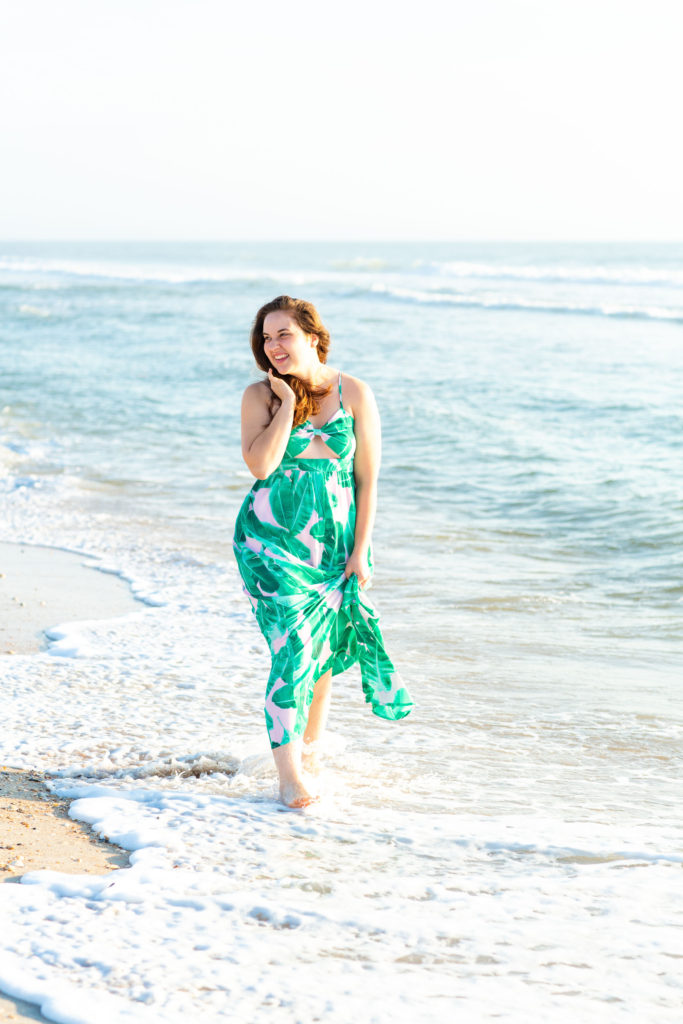 Brunette-Girl-Wearing-BuddyLove-Sirens-Song-Green-And-Pink-Tropical-Print-Maxi-Dress-With-Pink-Wicker-Round-Bag-At-Florida-Beach