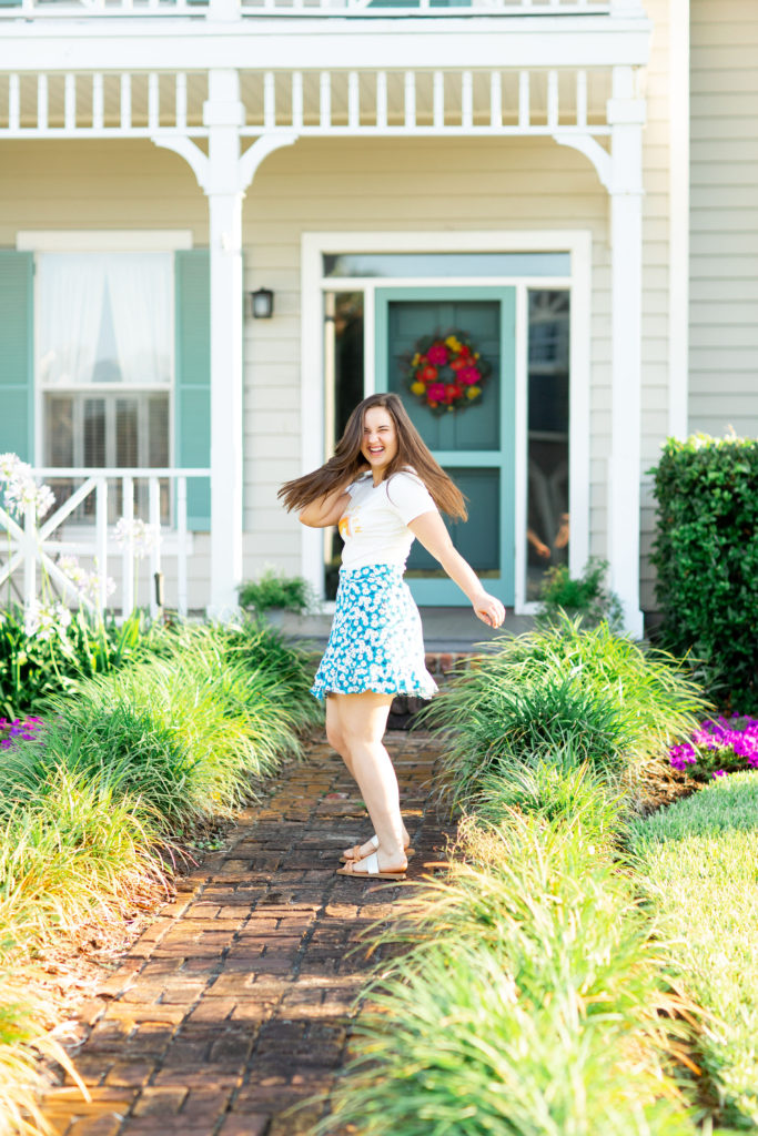 Brunette-Girl-Wearing-Stay-Golden-Graphic-Tee-And-Blue-Floral-Wrap-Skirt-From-Madison-And-Mallory