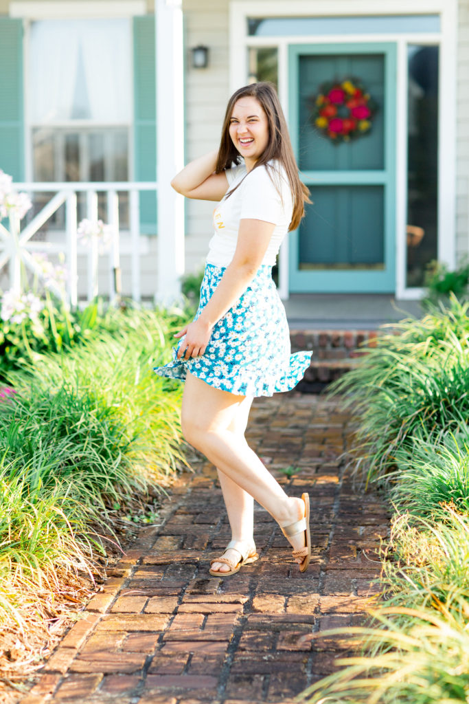 Brunette-Girl-Wearing-Stay-Golden-Graphic-Tee-And-Blue-Floral-Wrap-Skirt-From-Madison-And-Mallory