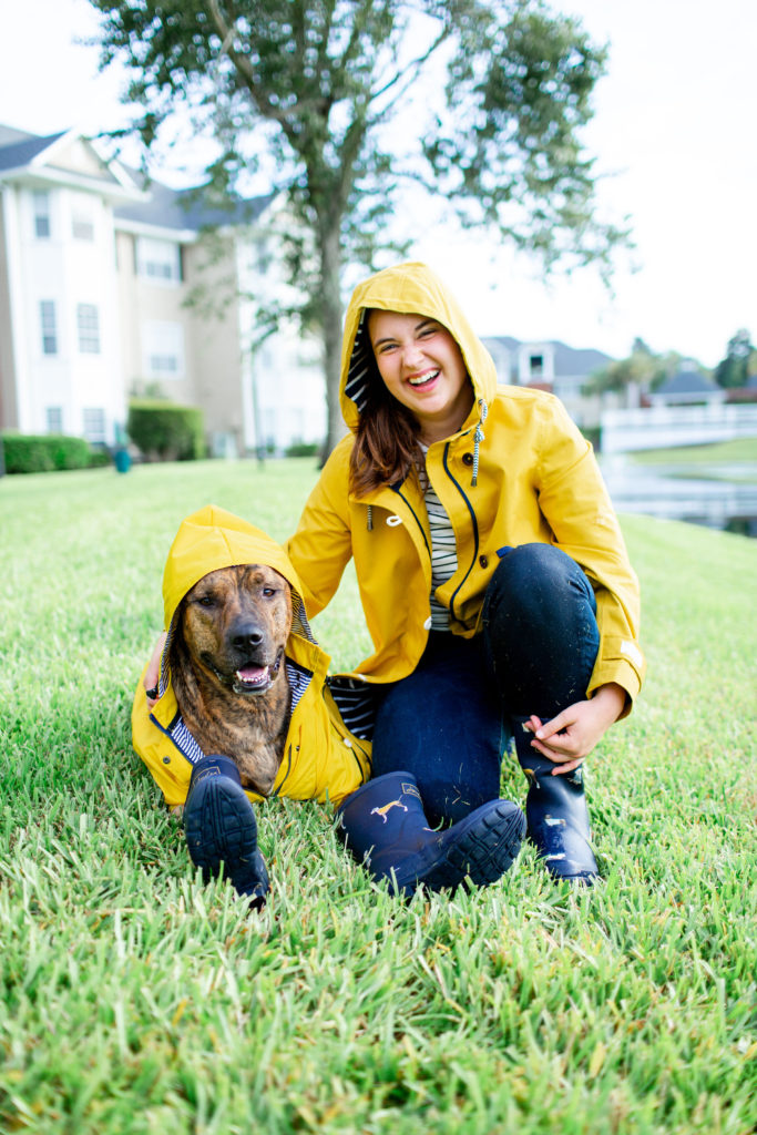 Girl-Wearing-Joules-Yellow-Raincoat-With-Mid-Calf-Blue-Dog-Rainboots-With-Brindle-Dog-Wearing-Yellow-Raincoat-From-amazon-And-Blue-Joules-Rainboots-How-To-Prepare-Your-Pets-For-Hurricane-Season
